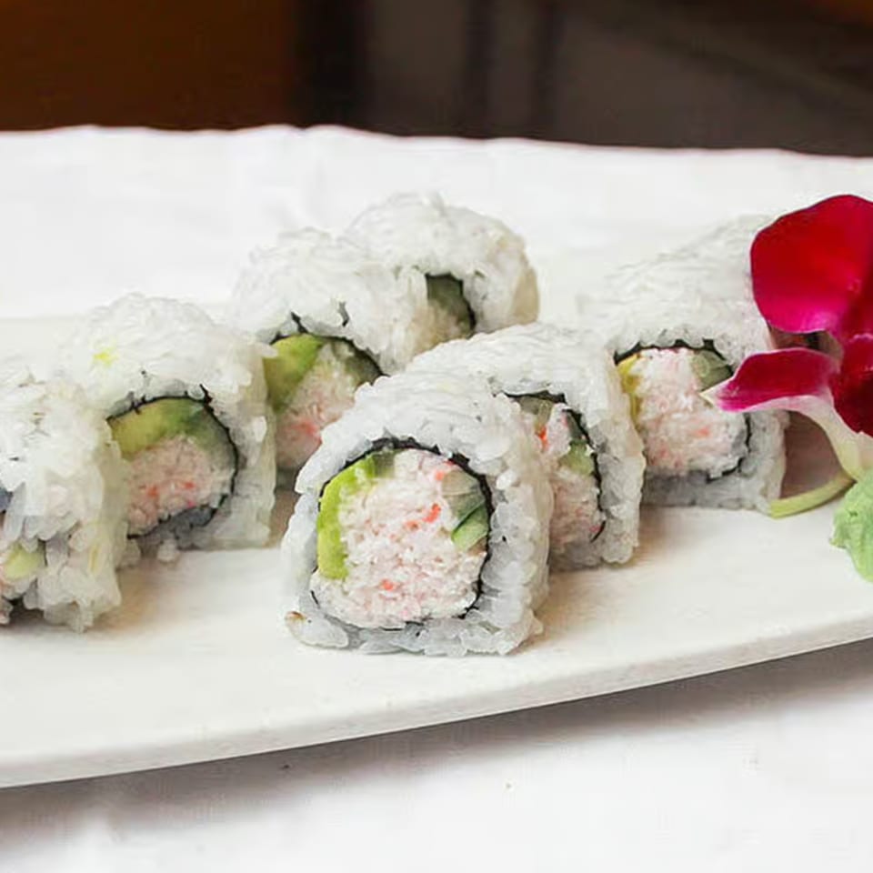 Sake Sushi + Grill's California rolls with crab, avocado, and rice, garnished with a red orchid.